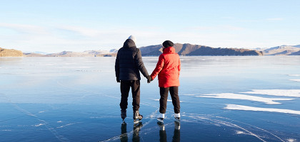 Пара катается на коньках по замерзшему Байкалу