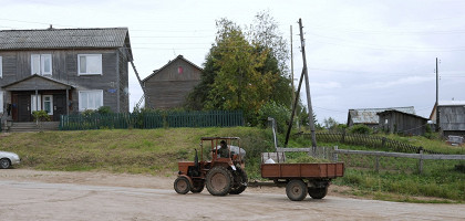 Трактор с прицепом едет по дороге в сельской местности. Деревня Ломоносово, Россия