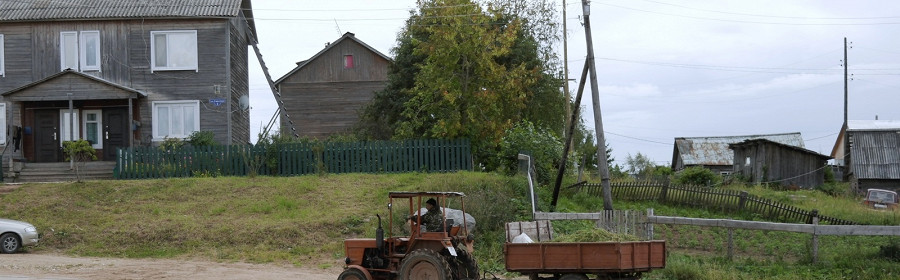 Трактор с прицепом едет по дороге в сельской местности. Деревня Ломоносово, Россия