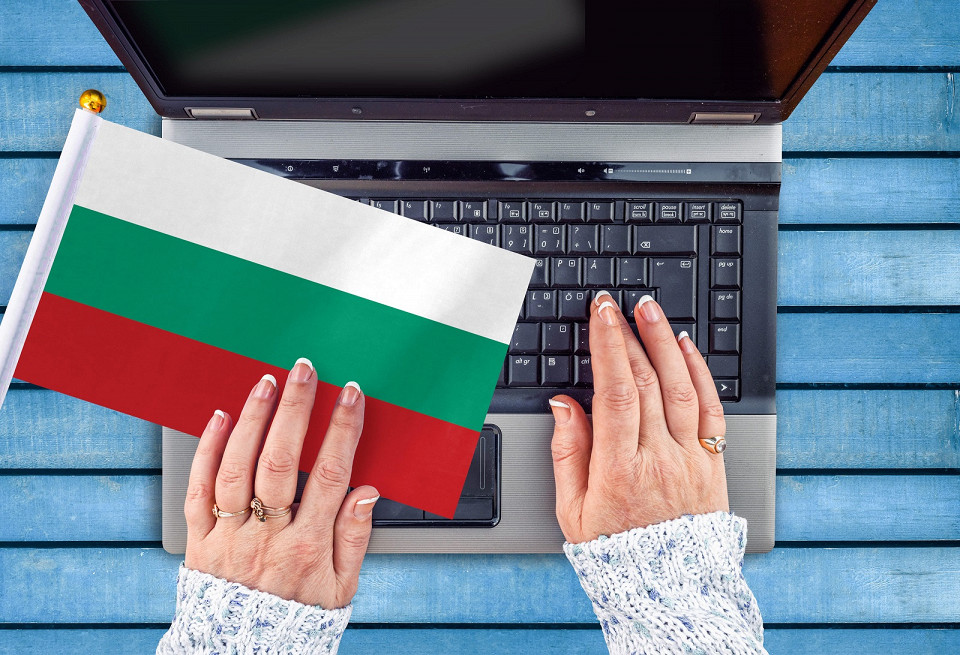 Женские руки и флаг Болгарии на компьютере, клавиатуре