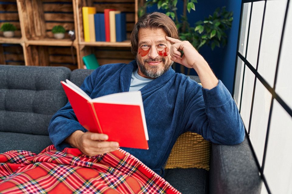 Мужчина в халате читает книгу на диване
