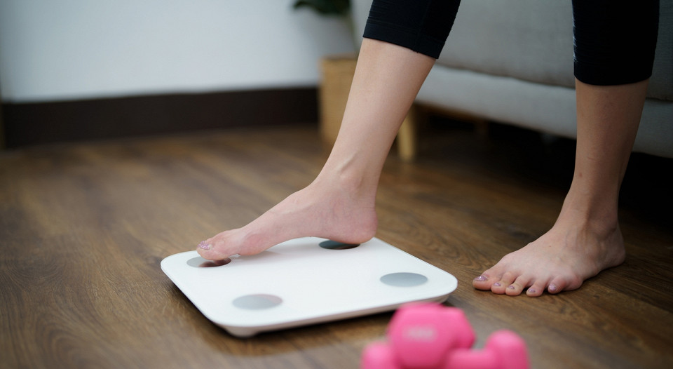 Женщина опасливо встает на весы