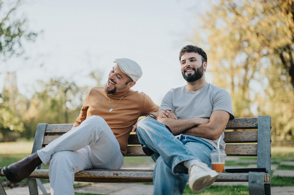 Мужчин отдыхают на скамейке в парке, друзья