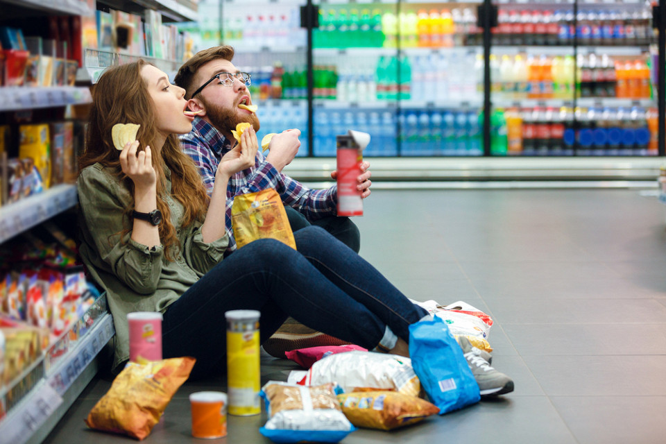 Парень и девушка едят в продуктовом магазине