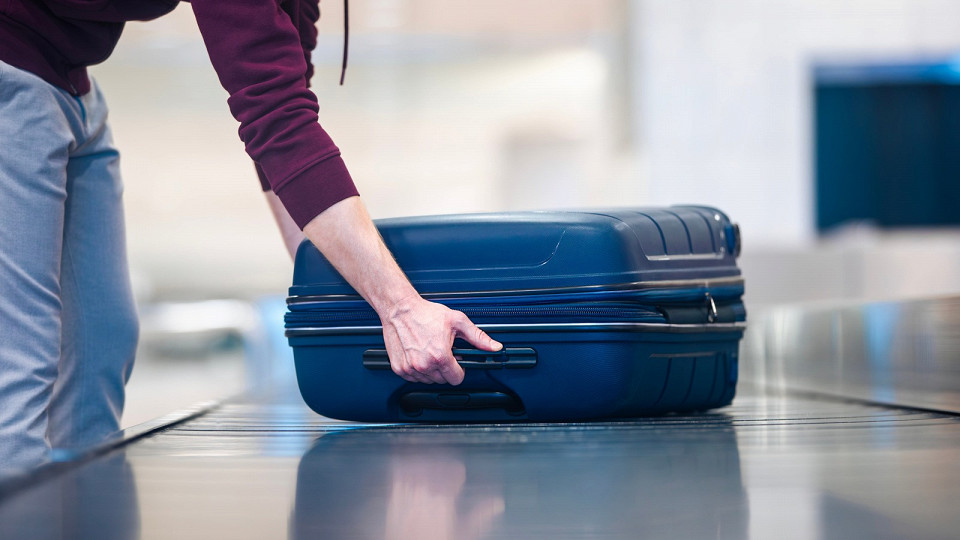 Мужчина берет синий чемодан