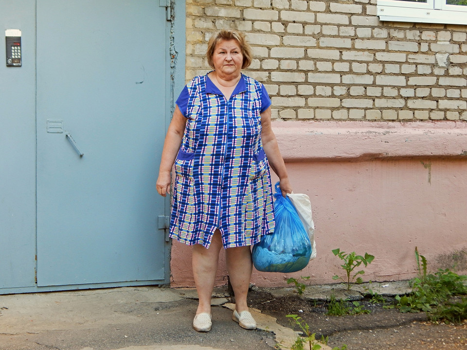 Женщина в халате выносит мусор