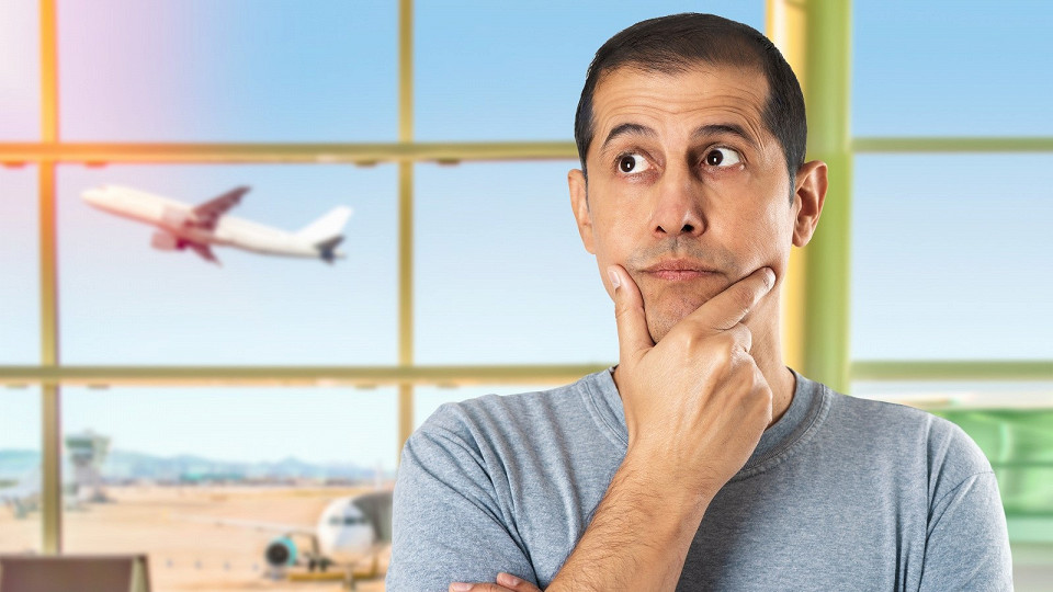 Турист в аэропорту, самолет за окном