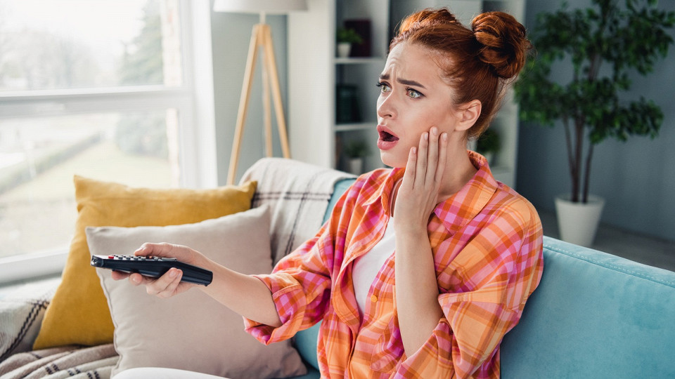 Девушка взволнованно смотрит телевизор