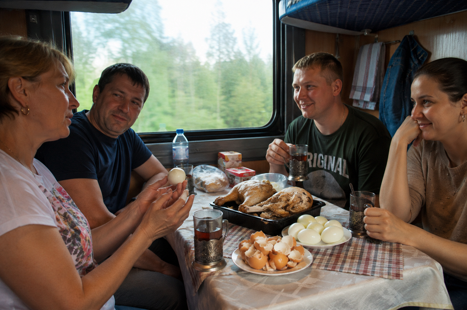 Попутчики в купе поезда едят курицу и яйца